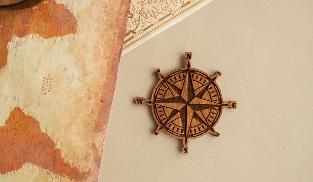 Wooden compass rose and vintage map on beige background, perfect for travel themes.